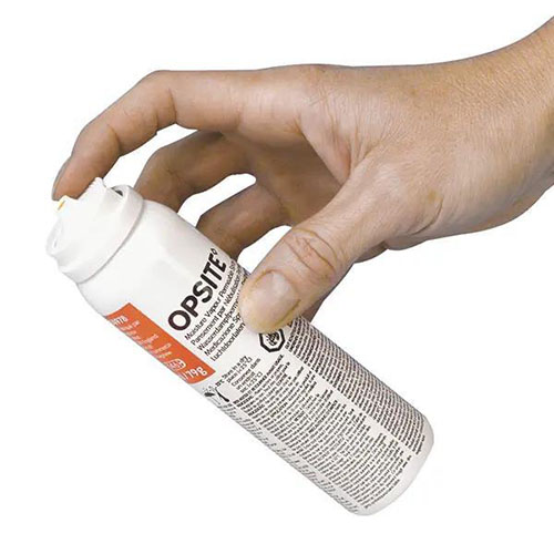 opsite spray sprühverband der von einer Hand zum sprühen angesetzt wird. Die Sprühfalsche ist weiß  mit schwarzer Schrift und orangenen Akzenten.jpg